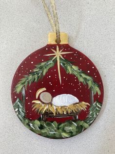 a christmas ornament with a nativity scene hanging from a cord on a wall