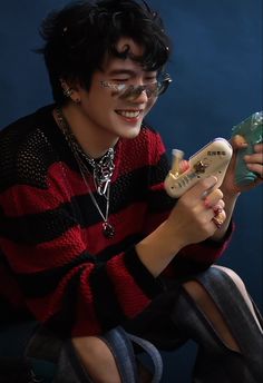 a young man sitting on the ground holding a remote control