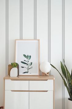 a white dresser with a plant on top and a potted plant next to it