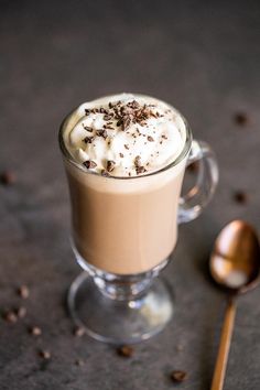 a glass cup filled with whipped cream and chocolate shavings next to a spoon