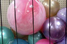 several balloons are in a cage on the floor and one is pink, purple, blue