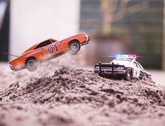 two toy cars are in the sand near each other