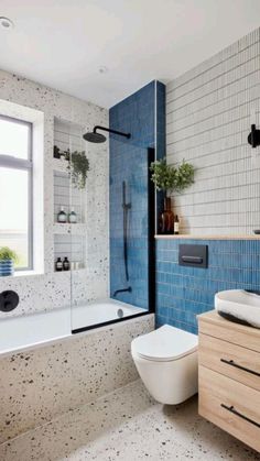 a modern bathroom with blue and white tiles on the walls, toilet, bathtub and sink