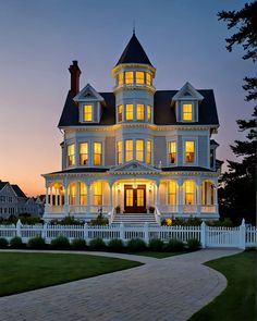 a large white house with lots of windows and lights on it's front porch