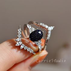 someone is holding a ring with a blue stone in it and some diamonds on the side