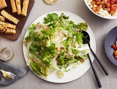 a white plate topped with lettuce next to other plates of food