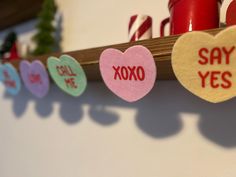 valentine's day candy hearts are hung on a wall with candles in the background