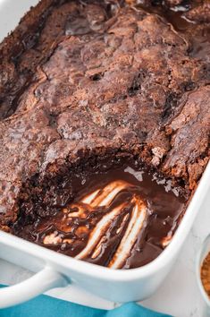 a close up of a cake in a pan with melted chocolate on top and other desserts around it