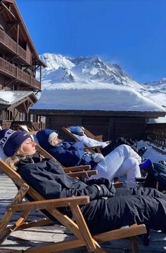 two people are lounging in chairs on the snow