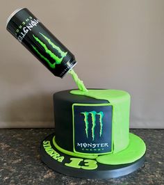 a birthday cake with a monster logo on it and a can being poured into the top