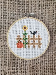 a cross stitch pattern with a bird on a fence and sunflower in the background