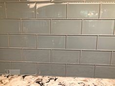 a kitchen counter top with white tiles on the backsplash and granite counter tops