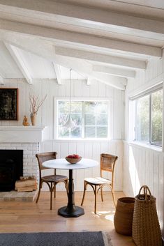 a white table and two chairs in a room with wood flooring on the walls