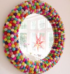 a colorful wreath made out of pom - poms is hanging on the wall