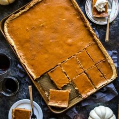 pumpkin pie sitting on top of a table next to other desserts and plates with forks