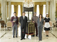 a group of people standing around each other in a room with chandelier and chairs