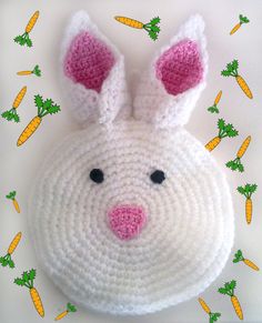 a crocheted bunny head laying on top of carrots