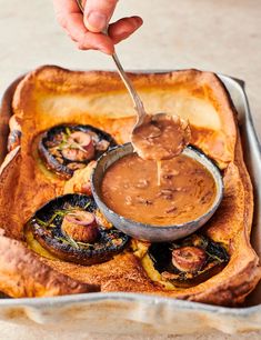 a person dipping something into a dish with some food on it and a spoon in the bowl