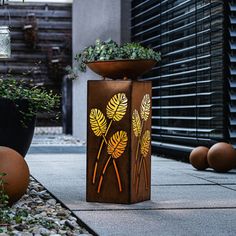 a planter sitting on top of a sidewalk next to potted plants