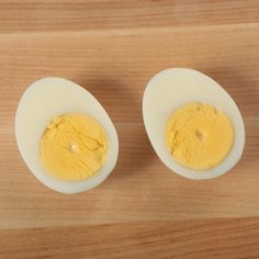 two hard boiled eggs sitting on top of a wooden table