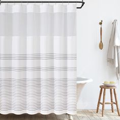 a bathroom with a bathtub, stool and shower curtain in white colors on the wall