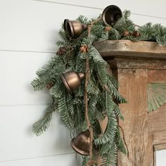 bells hanging from the side of a building with pine cones and evergreen branches on it