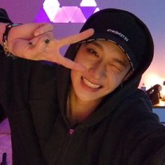 a young man making the peace sign with his hand while wearing a black hoodie