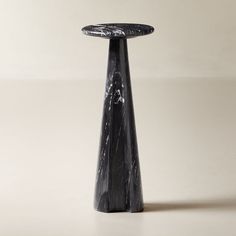 a black marble pedestal on a white surface with one leg up and the other end down