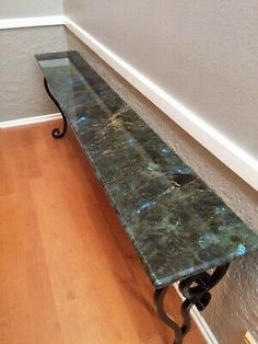 a marble bench sitting on top of a hard wood floor next to a white wall