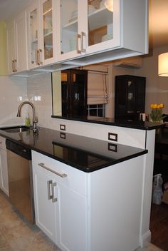 a kitchen with white cabinets and black counter tops