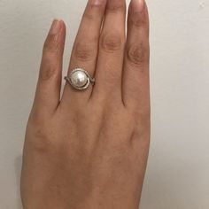 a woman's hand with a pearl ring on it