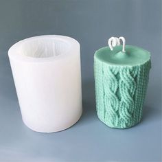 there are two candles that are next to each other on the same candle holder, one is green and the other is white