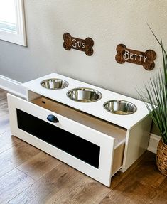 a white dog house with three bowls on the counter