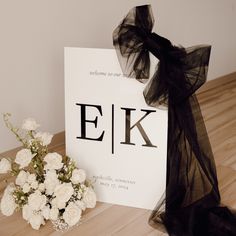 a bouquet of white flowers sitting on top of a wooden floor next to a sign