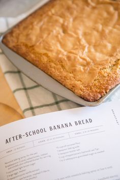 a banana bread sitting on top of a table next to a recipe book and utensils