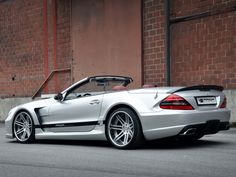 a silver sports car parked in front of a brick building