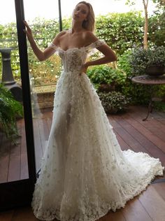 a woman standing in front of a mirror wearing a wedding dress with flowers on it