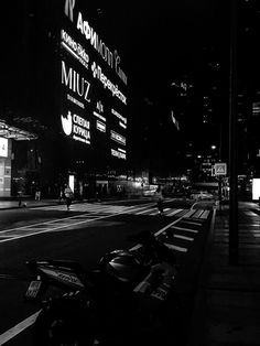 a black and white photo of a motorcycle parked on the side of the road at night