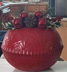 a red vase filled with ornaments on top of a table