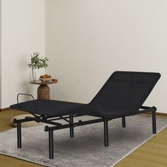 a black chaise lounger sitting on top of a rug in front of a white wall