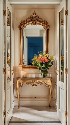 a vase with flowers sitting on top of a table next to a mirror and door