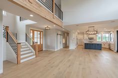 a large open floor plan with wood floors and white walls, stairs leading up to the kitchen