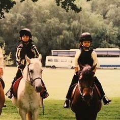 three children are riding horses in the grass