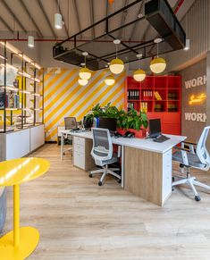 an office with yellow and white stripes on the walls, desks and chairs in front of them