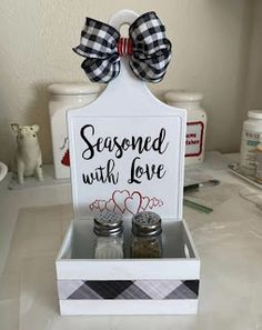 a sign that says seasoned with love and two jars filled with seasoning sit on a counter