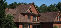 a red brick house with brown shingles and windows