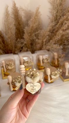 a hand holding a tiny bottle with flowers in it and some small bottles on the table