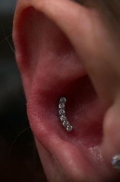 a woman's ear is shown with three small diamonds in the middle of it