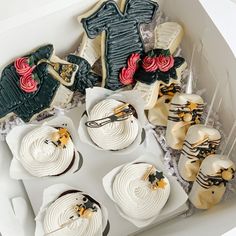 decorated cookies and cupcakes in a box on a table with plastic wrappers