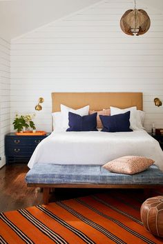 a bedroom with white walls and wood flooring is decorated in shades of blue, orange, and gold